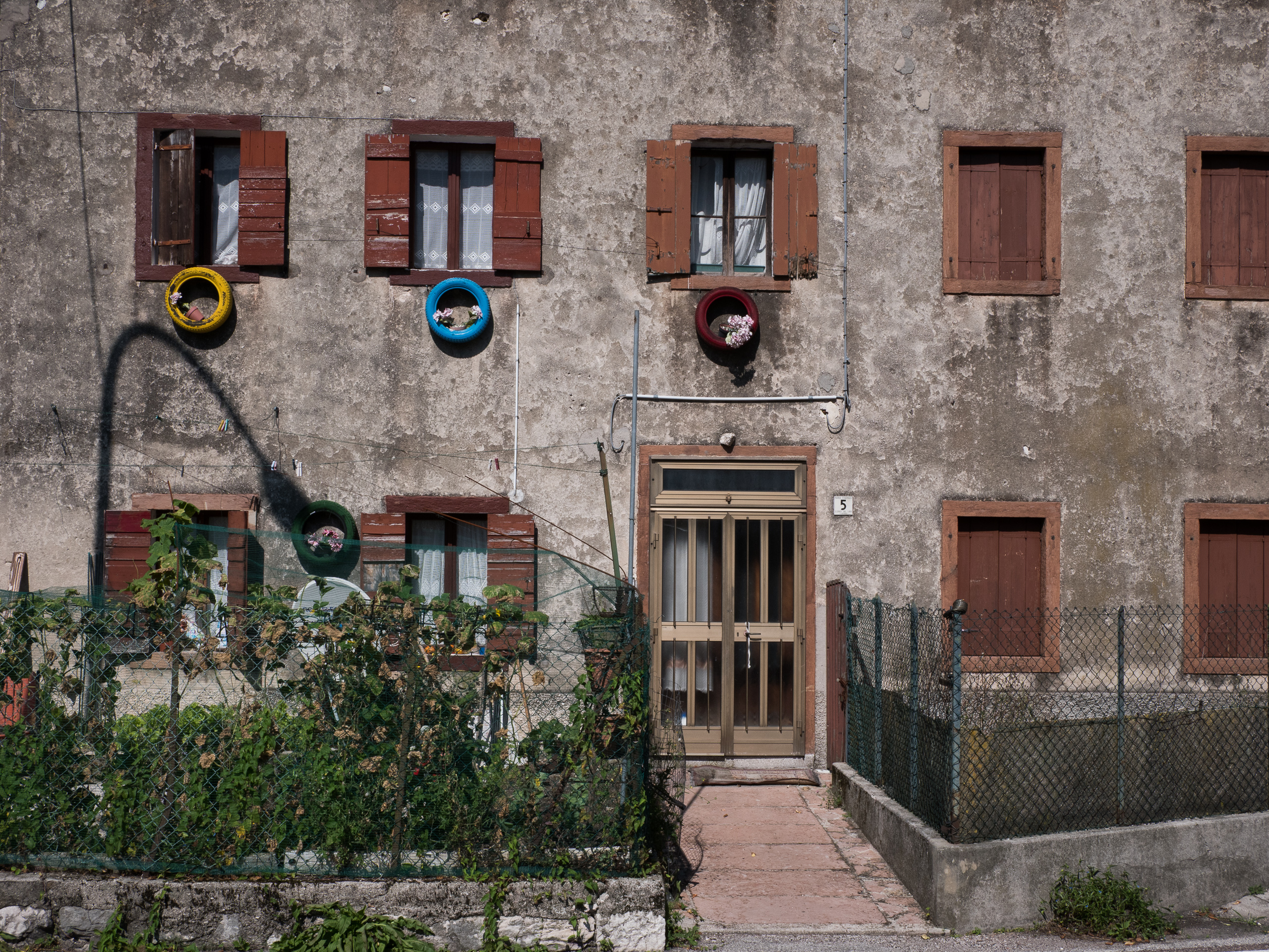 Hausfassade mit bunten Autoreifen als Blumentöpfe
